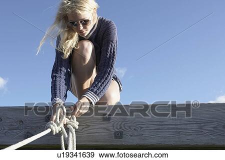 Young woman undoing ropes on jetty. View Large Photo Image Stock Photo - Young woman undoing ropes on jetty.. Fotosearch