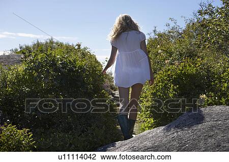 Stock Image - Young woman walking away from camera.. Fotosearch