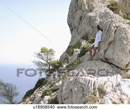 Woman leaning on large rocks looking out over the sea. View Large Photo Image Stock Image - Woman leaning on large rocks looking out over the sea.. Fotosearch