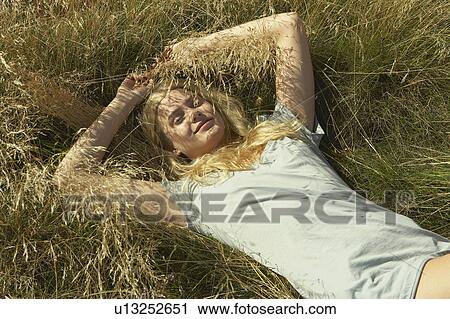 Young woman lying in long grass. View Large Photo Image Stock Image - Young woman lying in long grass.. Fotosearch