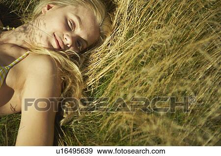 Young woman lying in long grass. View Large Photo Image Stock Photo - Young woman lying in long grass.. Fotosearch