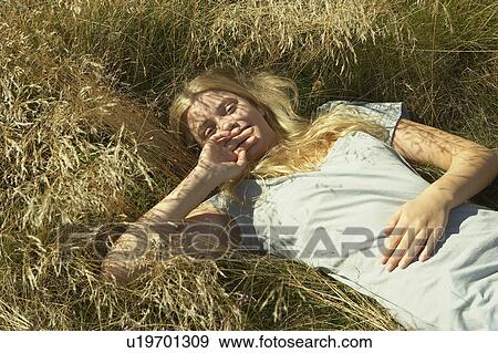 Young woman lying in long grass. View Large Photo Image Stock Photo - Young woman lying in long grass.. Fotosearch