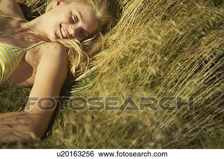 Stock Photograph - Young woman lying in long grass.. Fotosearch