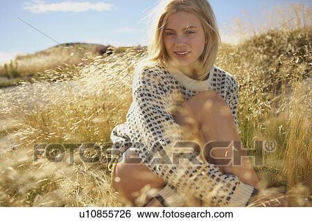 Stock Photograph - Young Woman Sitting in Long grass.. Fotosearch