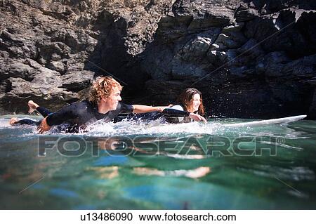 Couple lying on surfboards in the water smiling. View Large Photo Image Stock Image - Couple lying on surfboards in the water smiling.. Fotosearch