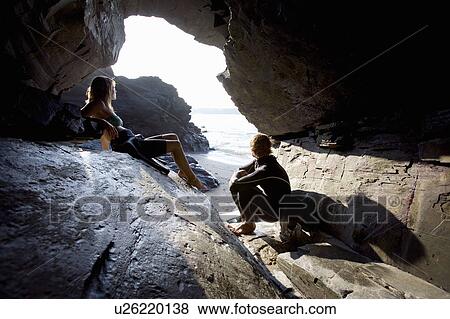 Couple sitting on large rocks in wetsuits. View Large Photo Image Stock Photo - Couple sitting on large rocks in wetsuits.. Fotosearch