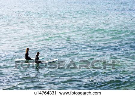 Couple sitting on surfboards in the water. View Large Photo Image Stock Image - Couple sitting on surfboards in the water.. Fotosearch