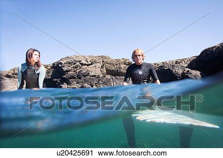 Couple sitting on surfboards in the water. View Large Photo Image Stock Image - Couple sitting on surfboards in the water.. Fotosearch