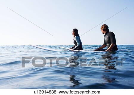 Couple sitting on surfboards in the water. View Large Photo Image Stock Photo - Couple sitting on surfboards in the water.. Fotosearch