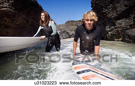 Couple standing in water with surfboards smiling. View Large Photo Image Stock Image - Couple standing in water with surfboards smiling.. Fotosearch