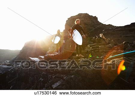Couple standing on large rocks with surfboards. View Large Photo Image Stock Photograph - Couple standing on large rocks with surfboards.. Fotosearch
