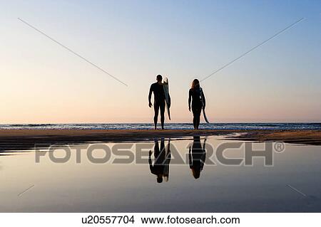 Couple standing on the beach with surfboards. View Large Photo Image Picture - Couple standing on the beach with surfboards.. Fotosearch