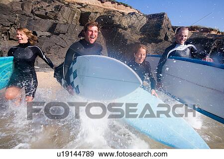 Four people running into the water with surfboards smiling. View Large Photo Image Stock Photo - Four people running into the water with surfboards smiling.. Fotosearch