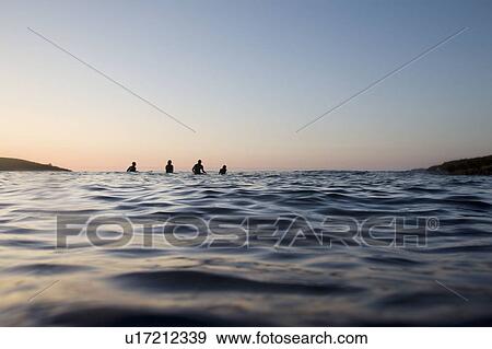 Four people sitting on surfboards in the water. View Large Photo Image Stock Photo - Four people sitting on surfboards in the water.. Fotosearch