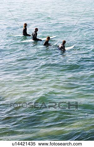 Four people sitting on surfboards in the water. View Large Photo Image Stock Photography - Four people sitting on surfboards in the water.. Fotosearch