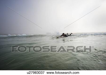 Man lying on surfboard in the water. View Large Photo Image Stock Photo - Man lying on surfboard in the water.. Fotosearch