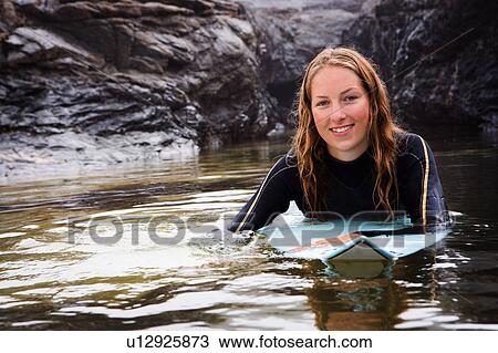 Woman lying on surfboard in the water smiling. View Large Photo Image Stock Image - Woman lying on surfboard in the water smiling.. Fotosearch