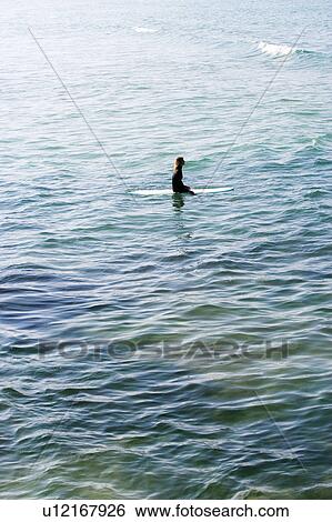 Woman sitting on surfboard in the water. View Large Photo Image Stock Photograph - Woman sitting on surfboard in the water.. Fotosearch