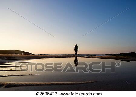 Woman standing on the beach holding surfboard. View Large Photo Image Stock Image - Woman standing on the beach holding surfboard.. Fotosearch