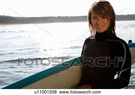 Stock Photo - Woman standing with a surfboard.. Fotosearch