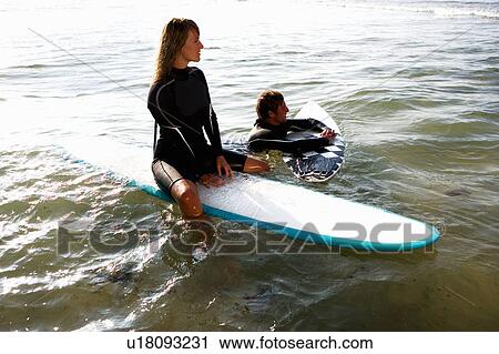 Couple floating on surfboards in the water smiling. View Large Photo Image Stock Image - Couple floating on surfboards in the water smiling.. Fotosearch