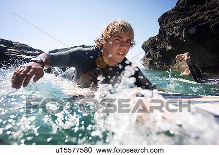 Couple lying on surfboards in the water smiling. View Large Photo Image Stock Image - Couple lying on surfboards in the water smiling.. Fotosearch