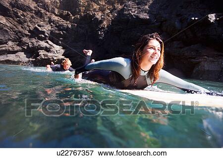 Couple lying on surfboards in the water smiling. View Large Photo Image Stock Photo - Couple lying on surfboards in the water smiling.. Fotosearch