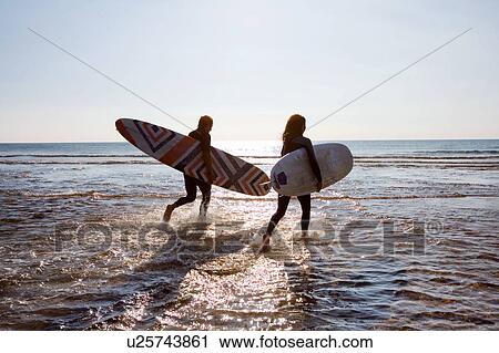 Couple running in water carrying surfboards. View Large Photo Image Stock Image - Couple running in water carrying surfboards.. Fotosearch