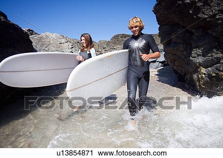 Couple running in water with surfboards smiling. View Large Photo Image Stock Image - Couple running in water with surfboards smiling.. Fotosearch