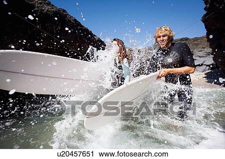 Couple running in water with surfboards smiling. View Large Photo Image Stock Image - Couple running in water with surfboards smiling.. Fotosearch