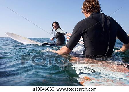 Couple sitting on surfboards in the water. View Large Photo Image Stock Photograph - Couple sitting on surfboards in the water.. Fotosearch