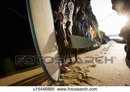 Couple standing with surfboards by large rocks. View Large Photo Image Stock Photography - Couple standing with surfboards by large rocks.. Fotosearch