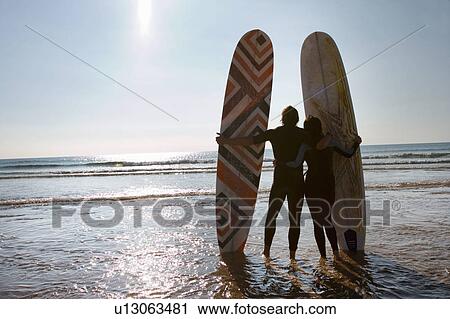 Couple with surfboards standing on beach. View Large Photo Image Stock Image - Couple with surfboards standing on beach.. Fotosearch