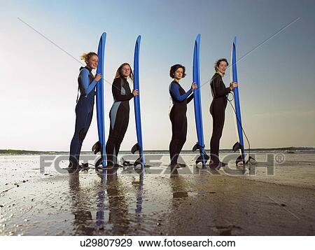 Four female surfers standing on a beach. View Large Photo Image Stock Photo - Four female surfers standing on a beach.. Fotosearch