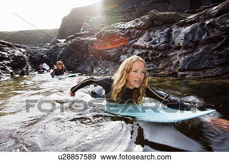 Four people lying on surfboards in the water smiling. View Large Photo Image Stock Photo - Four people lying on surfboards in the water smiling.. Fotosearch