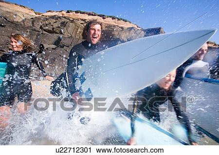 Four people running into the water with surfboards smiling. View Large Photo Image Stock Image - Four people running into the water with surfboards smiling.. Fotosearch