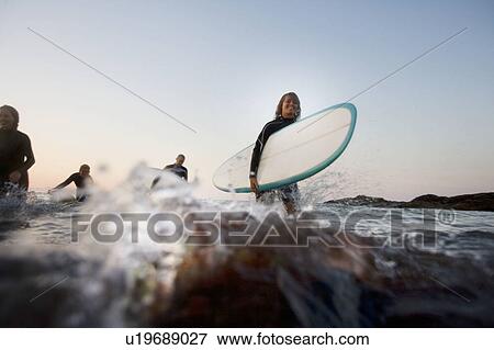 Four people with surfboards in the water. View Large Photo Image Stock Photo - Four people with surfboards in the water.. Fotosearch