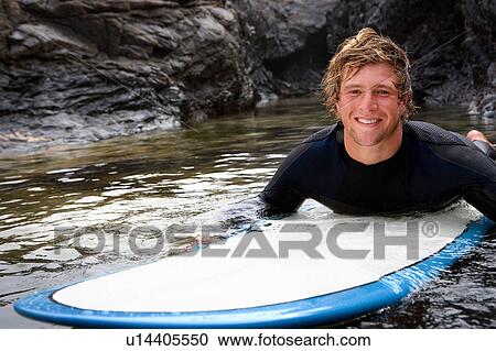 Man lying on surfboard in the water smiling. View Large Photo Image Stock Image - Man lying on surfboard in the water smiling.. Fotosearch