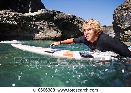 Man lying on surfboard in the water smiling. View Large Photo Image Stock Photo - Man lying on surfboard in the water smiling.. Fotosearch