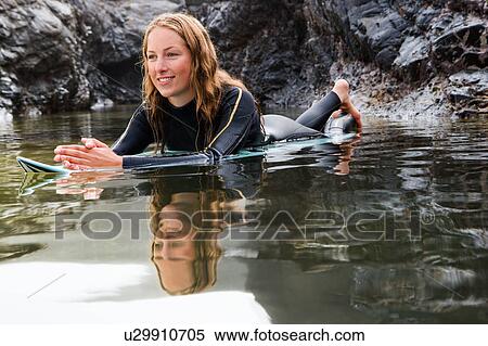 Woman lying on surfboard in the water smiling. View Large Photo Image Stock Photography - Woman lying on surfboard in the water smiling.. Fotosearch