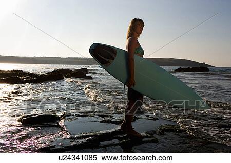 Woman standing in shallow water with surfboard. View Large Photo Image Stock Photography - Woman standing in shallow water with surfboard.. Fotosearch