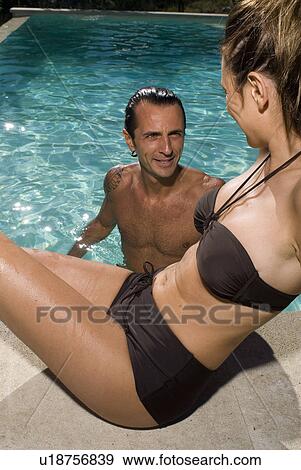 Couple at a pool where the man is in the water View Large Photo Image Stock Photo - Couple at a pool where the man is in the water. Fotosearch