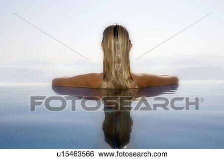 Woman leaning at the ledge of an infinity pool. View Large Photo Image Stock Photograph - Woman leaning at the ledge of an infinity pool.. Fotosearch