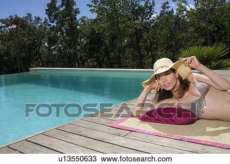 Woman lying on a wood deck by a swimming pool View Large Photo Image Stock Image - Woman lying on a wood deck by a swimming pool. Fotosearch