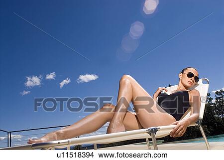 Woman sunbathing by a swimming pool View Large Photo Image Picture - Woman sunbathing by a swimming pool. Fotosearch