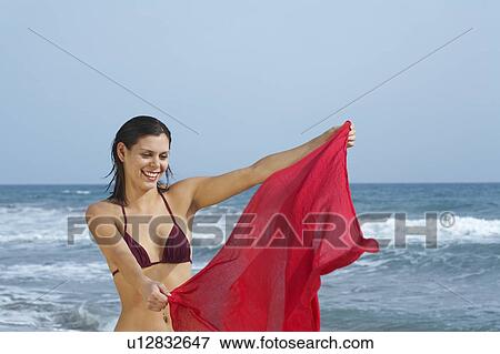 Stock Photo - Woman waving sarong in wind on beach.. Fotosearch