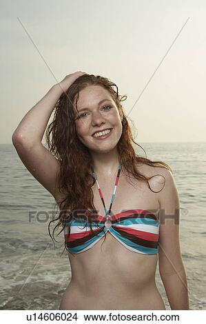 Picture - Woman with hand on head with sea beyond.. Fotosearch