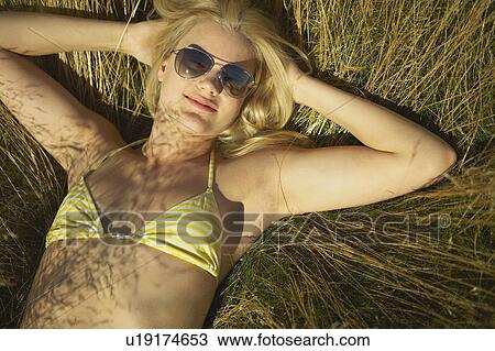 Stock Image - Young woman lying in long grass.. Fotosearch