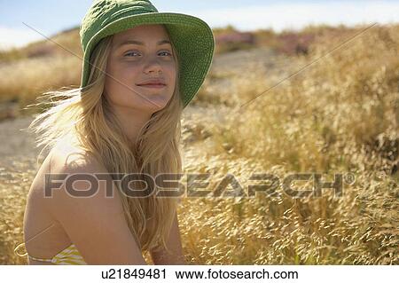 Stock Image - Young Woman Sitting in Long grass.. Fotosearch