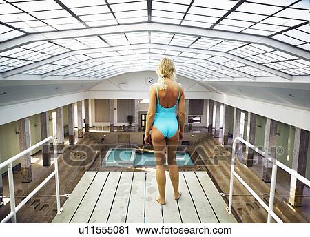 Stock Image - Mature woman standing on diving board, rear view. Fotosearch